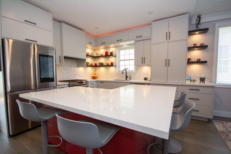 A kitchen with a white island and red stools.