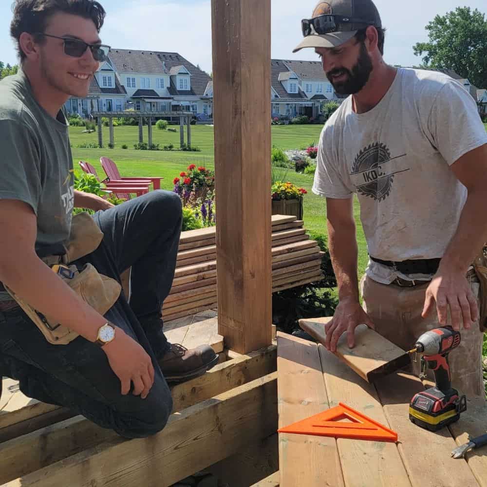 Two men working on a wooden deck.