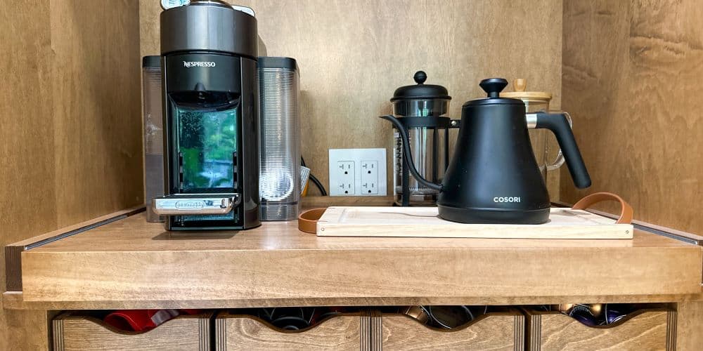 A coffee maker is on a shelf in a kitchen.